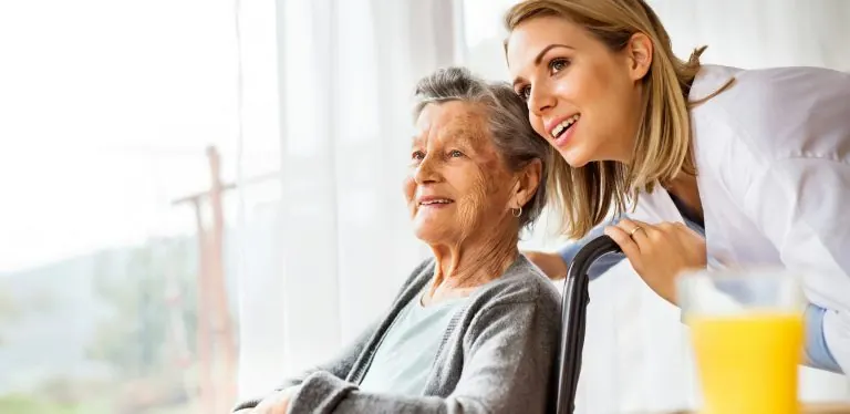 A carer chatting with an older woman by the window